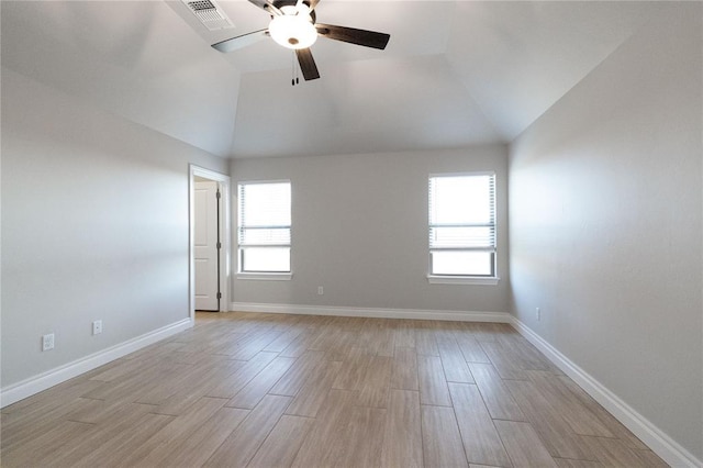 spare room with baseboards, a ceiling fan, visible vents, lofted ceiling, and light wood finished floors