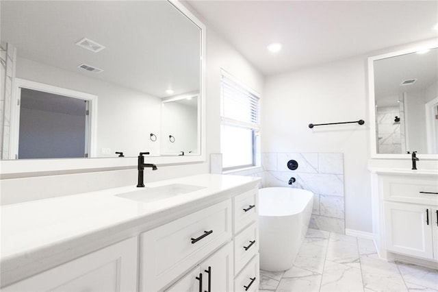 bathroom with a freestanding tub, marble finish floor, a sink, and visible vents