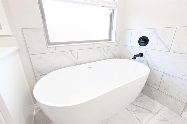 full bathroom with marble finish floor and a soaking tub
