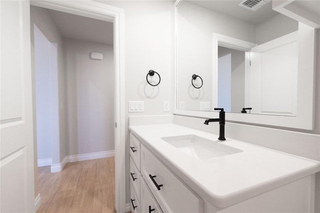 bathroom featuring vanity, visible vents, baseboards, and wood finished floors