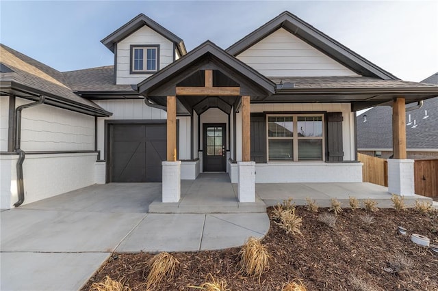 view of front of house with a shingled roof, driveway, fence, and an attached garage