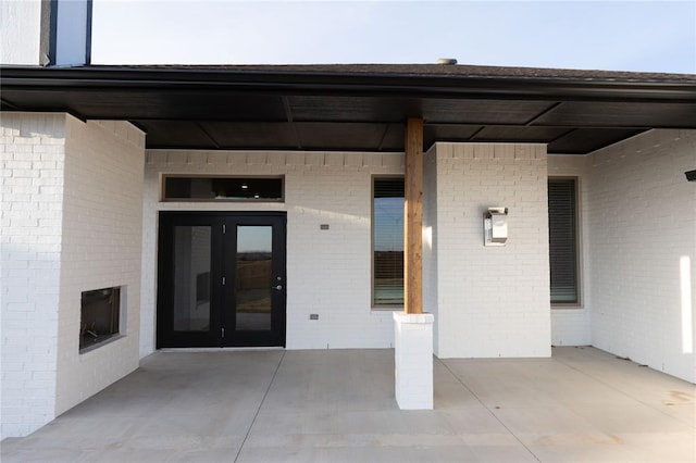view of exterior entry featuring a patio area and brick siding