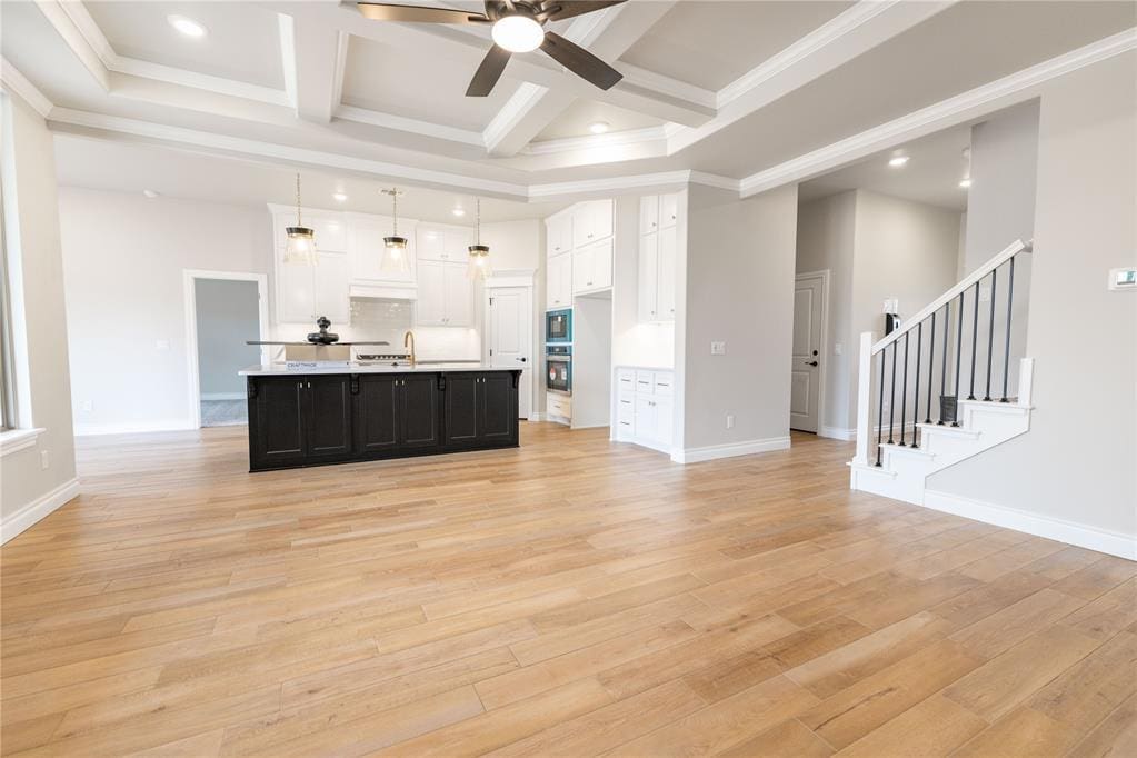 living room featuring beamed ceiling, sink, coffered ceiling, and light hardwood / wood-style floors