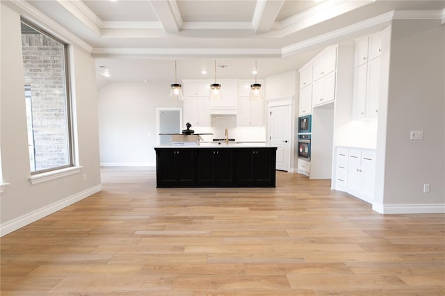 kitchen with sink, light hardwood / wood-style flooring, a kitchen island with sink, white cabinets, and decorative light fixtures