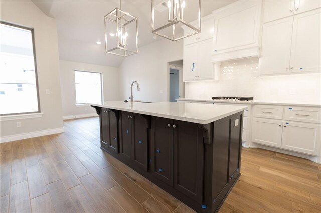 kitchen featuring a kitchen island with sink, sink, white cabinetry, and light hardwood / wood-style flooring