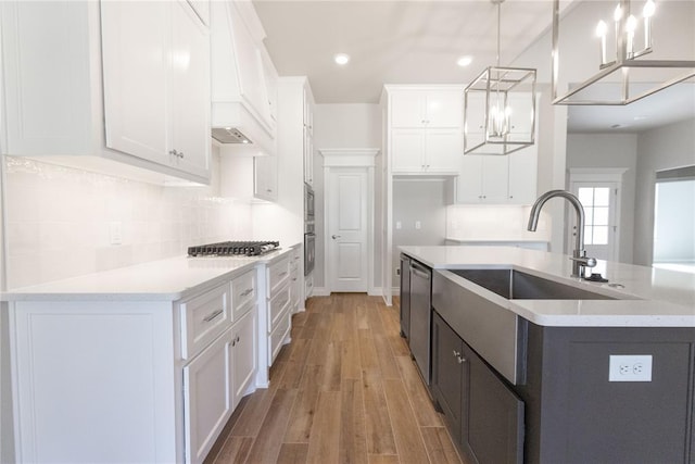 8709 Tyrion Dr, Edmond, OK 73007 - kitchen featuring light wood-style flooring, light countertops, custom range hood, white cabinets, and tasteful backsplash