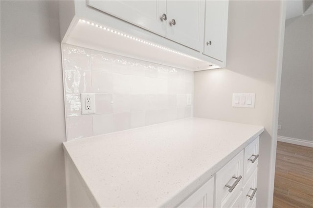 8709 Tyrion Dr, Edmond, OK 73007 - kitchen with baseboards, wood finished floors, white cabinets, and light stone countertops