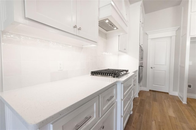 8709 Tyrion Dr, Edmond, OK 73007 - kitchen with light stone counters, wood finished floors, appliances with stainless steel finishes, white cabinetry, and backsplash