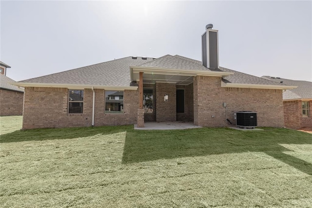 8709 Tyrion Dr, Edmond, OK 73007 - rear view of house featuring a yard, roof with shingles, central AC, and a patio area