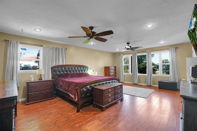 bedroom with hardwood / wood-style floors, ceiling fan, and multiple windows