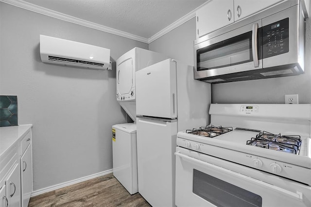 kitchen with white appliances, dark wood-type flooring, crown molding, an AC wall unit, and white cabinets