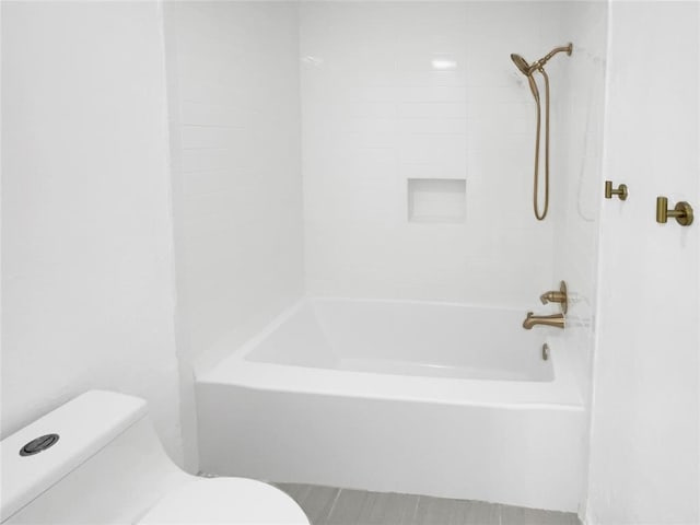 bathroom with tiled shower / bath combo and toilet