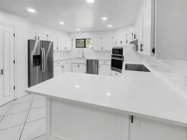 kitchen featuring white cabinets, sink, light tile patterned floors, appliances with stainless steel finishes, and kitchen peninsula