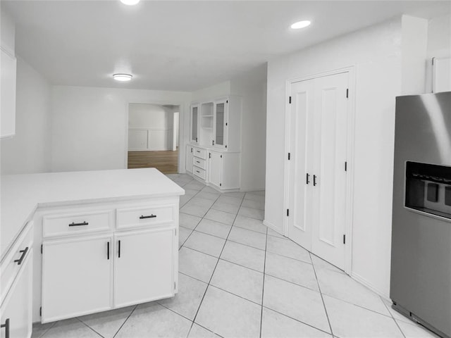 kitchen featuring stainless steel fridge with ice dispenser, white cabinetry, and light tile patterned flooring