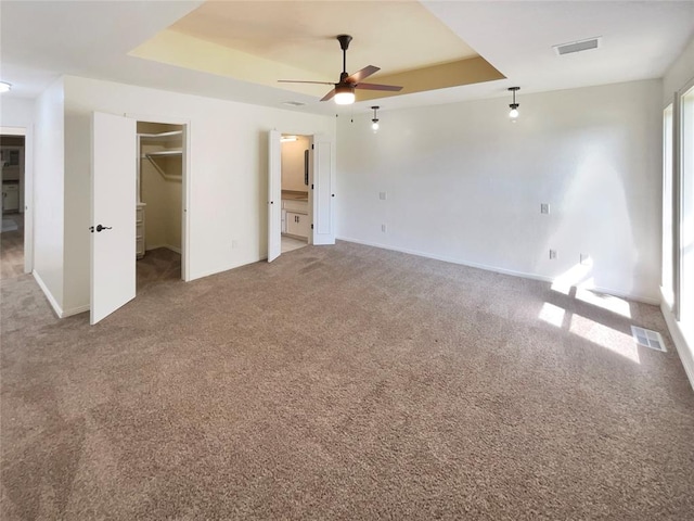 unfurnished bedroom featuring carpet, a walk in closet, a closet, and ceiling fan