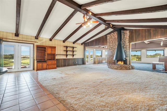 interior space featuring lofted ceiling with beams, a wood stove, plenty of natural light, and wood walls