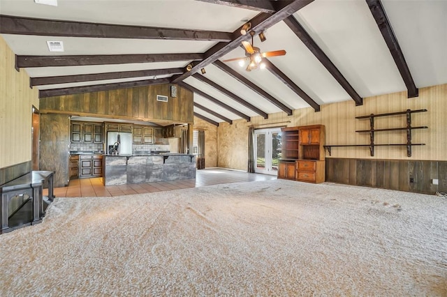 unfurnished living room featuring beam ceiling, wooden walls, ceiling fan, and high vaulted ceiling