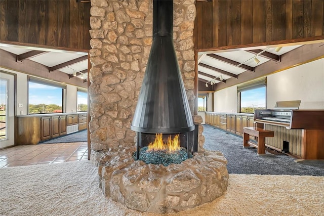 interior space with carpet, a wood stove, beamed ceiling, and a fire pit