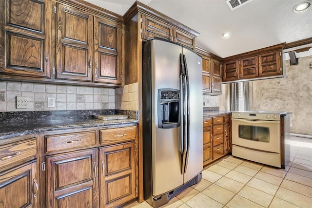 kitchen featuring backsplash, white electric range oven, light tile patterned flooring, and stainless steel refrigerator with ice dispenser