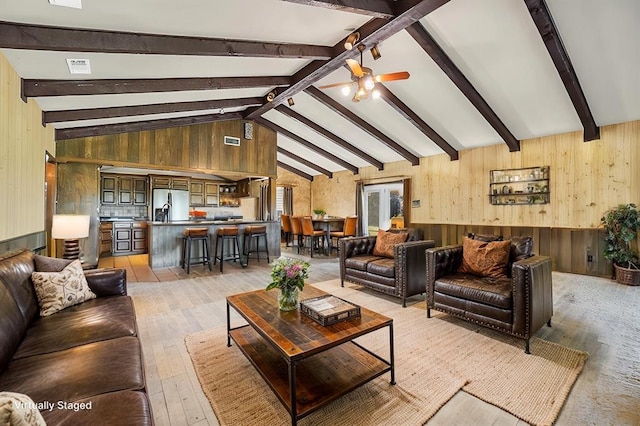 living room with beam ceiling, light hardwood / wood-style floors, ceiling fan, and wooden walls