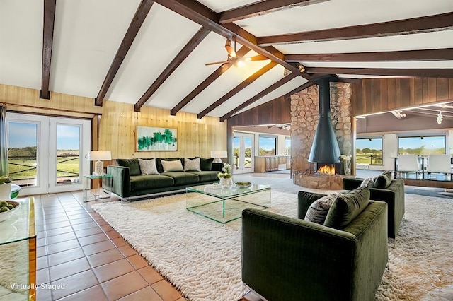 living room with beamed ceiling, a wood stove, plenty of natural light, and wooden walls