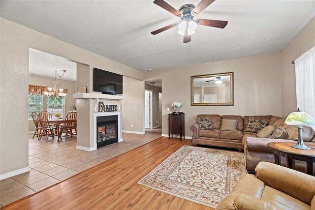 living room featuring ceiling fan with notable chandelier and light wood-type flooring