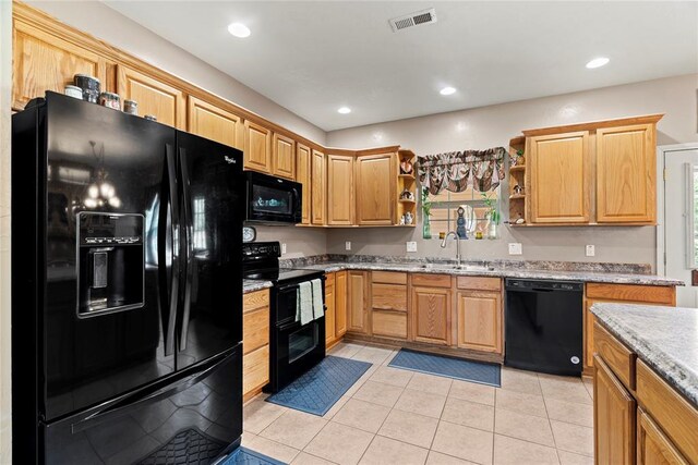 kitchen featuring black appliances, light tile patterned flooring, light stone countertops, and sink