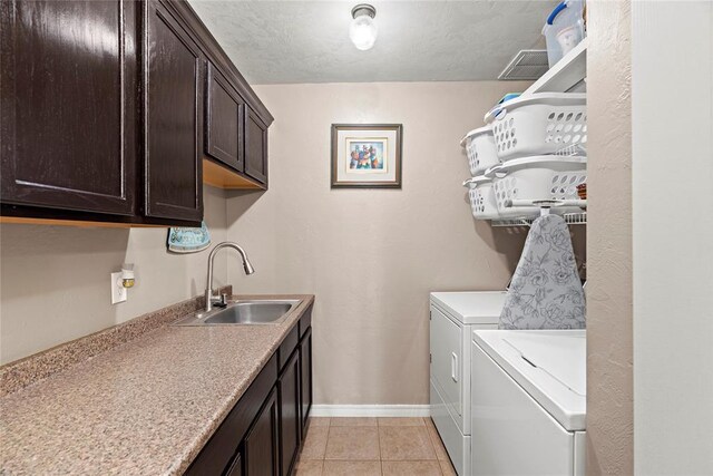 clothes washing area with cabinets, sink, separate washer and dryer, a textured ceiling, and light tile patterned floors