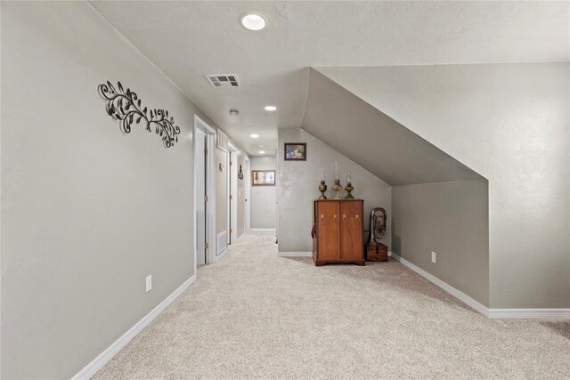 bonus room with light colored carpet and vaulted ceiling