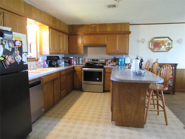 kitchen with a kitchen bar, stainless steel appliances, kitchen peninsula, and sink