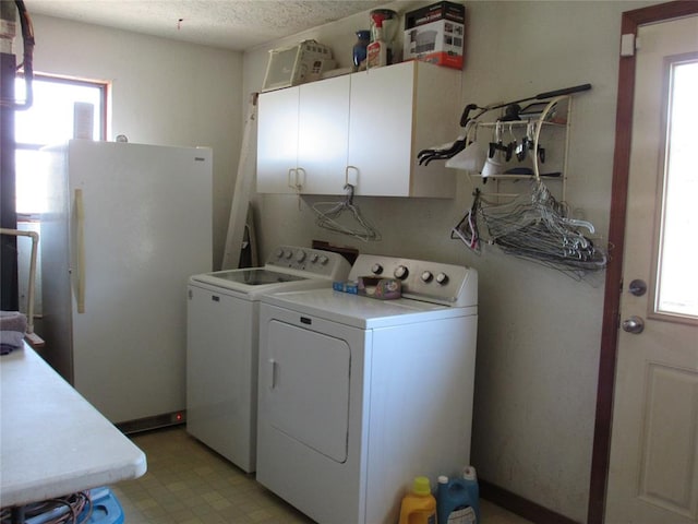 washroom featuring washing machine and dryer, cabinets, a healthy amount of sunlight, and a textured ceiling