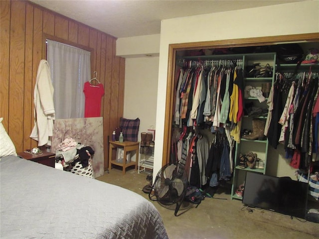 bedroom with wood walls, concrete floors, and a closet