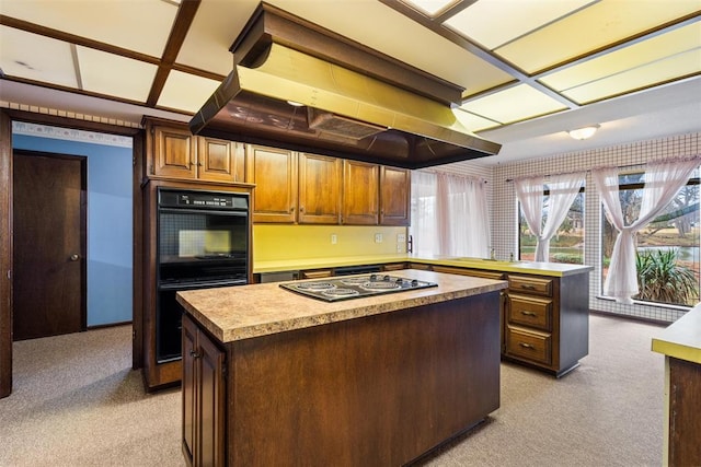 kitchen featuring a kitchen island, island range hood, light colored carpet, and black appliances