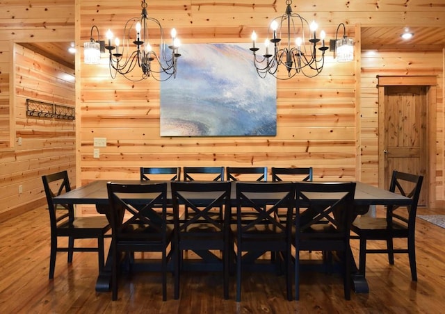 dining area with hardwood / wood-style floors, a notable chandelier, wooden ceiling, and wooden walls