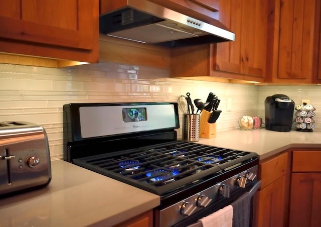 kitchen with black gas range, decorative backsplash, and range hood