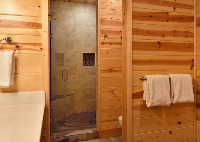 bathroom featuring wood walls, a shower with door, and toilet