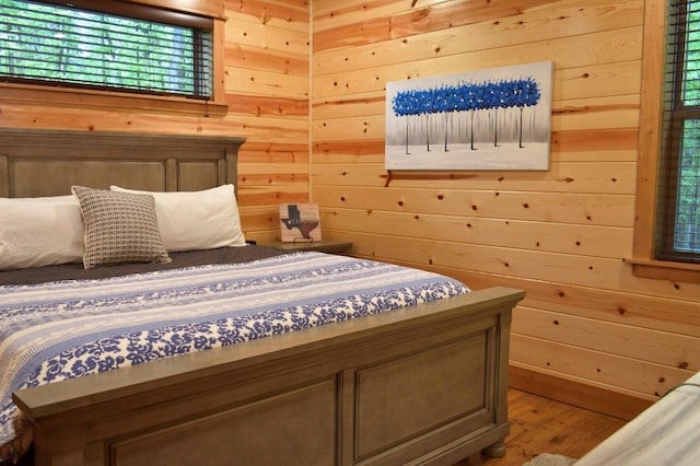 bedroom featuring hardwood / wood-style flooring and wood walls