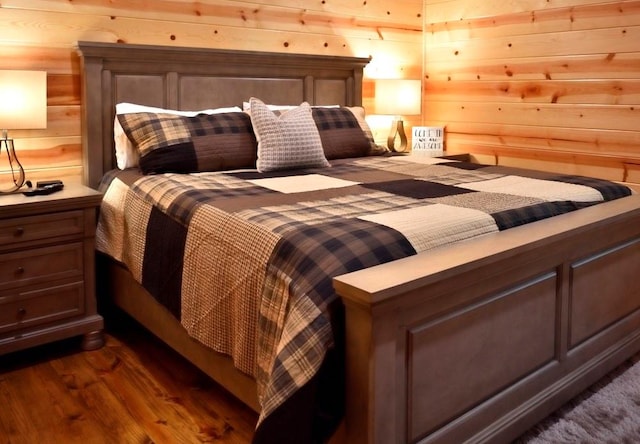 bedroom with wooden walls and dark hardwood / wood-style flooring