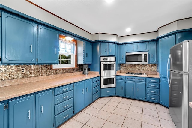 kitchen with blue cabinetry, appliances with stainless steel finishes, decorative backsplash, and light tile patterned floors