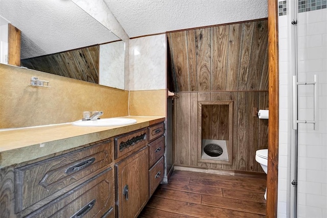 bathroom with hardwood / wood-style floors, a textured ceiling, toilet, and wood walls