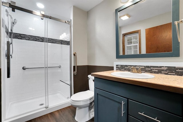 bathroom with hardwood / wood-style floors, vanity, backsplash, toilet, and walk in shower