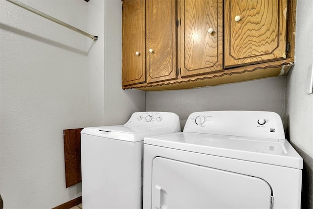 clothes washing area with cabinets and washing machine and clothes dryer