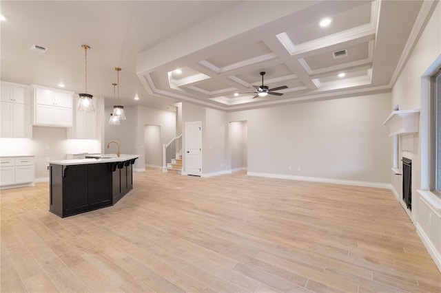 kitchen featuring a fireplace, light countertops, visible vents, light wood-style flooring, and an island with sink