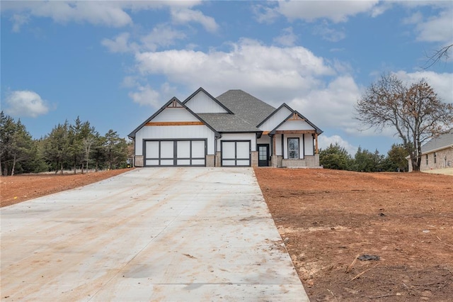 modern farmhouse featuring a shingled roof, concrete driveway, and an attached garage