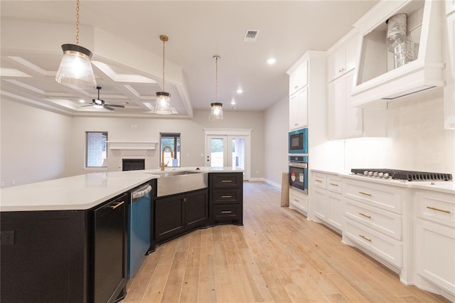 kitchen with stainless steel appliances, a sink, white cabinetry, light countertops, and light wood-type flooring