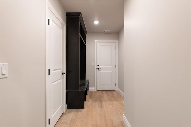 hall with light wood-type flooring, visible vents, and baseboards