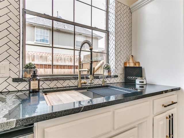 kitchen featuring decorative backsplash, sink, white cabinets, and stainless steel dishwasher