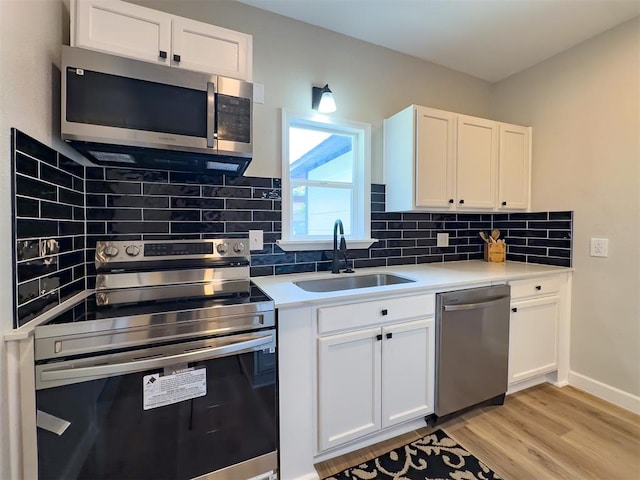 kitchen featuring sink, white cabinetry, stainless steel appliances, and light hardwood / wood-style flooring