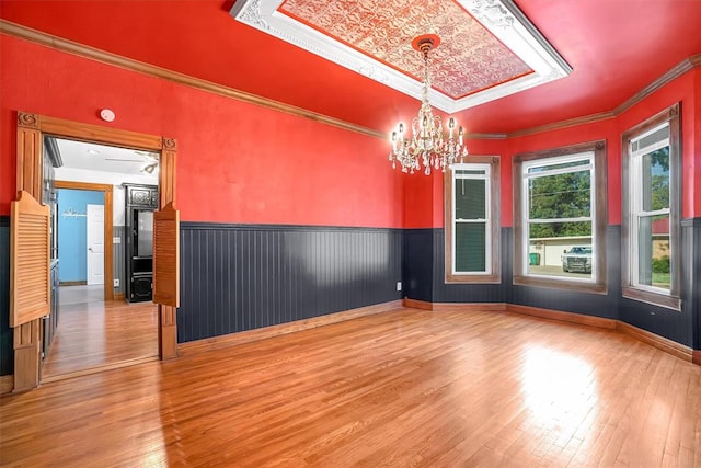 unfurnished room featuring hardwood / wood-style floors, ornamental molding, and a chandelier