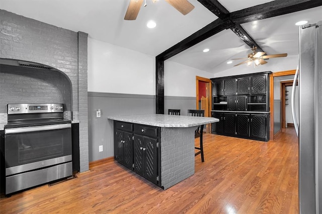 kitchen featuring a kitchen bar, appliances with stainless steel finishes, kitchen peninsula, lofted ceiling with beams, and light hardwood / wood-style floors